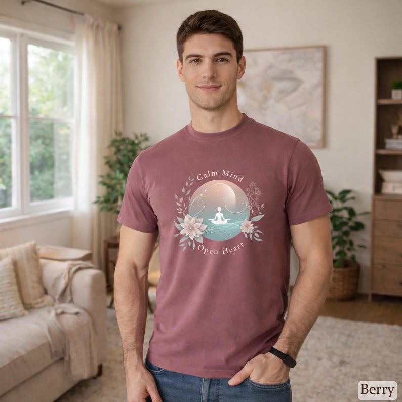 Puede incluir: Camiseta color bayas con un dise&ntilde;o gr&aacute;fico circular que presenta una figura meditando, flores y el texto "Calm Mind Open Heart". El dise&ntilde;o est&aacute; sobre un fondo degradado. La camiseta tiene mangas cortas y cuello redondo.