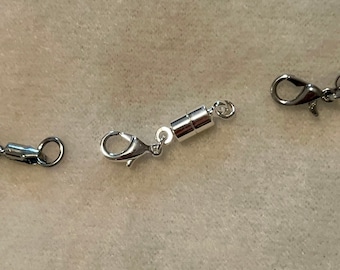 May include: Silver magnetic clasp for a necklace or bracelet. The clasp has two silver lobster claw clasps and a magnetic closure in the center.