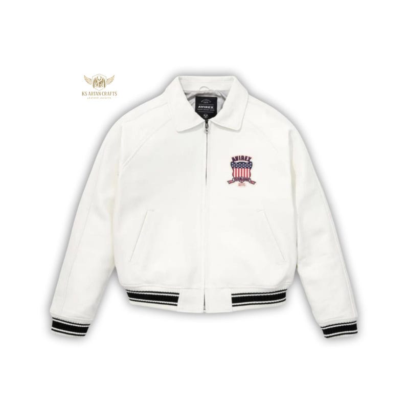 May include: White bomber jacket with a collar and a zipper closure. The jacket features black and white striped cuffs and hem. An embroidered emblem with the word "AVIREX" and a patriotic design is on the chest.