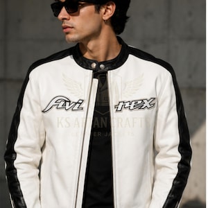 May include: White leather jacket with black accents on the shoulders and sleeves. The jacket features the text "Avi Rex" on the chest and "KS AAN CRAFT LEATHER JACKETS" below. The jacket has a zipper closure and a round collar.
