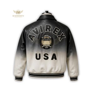 K&ouml;nnte beinhalten: Schwarz-wei&szlig;e Lederjacke mit dem Text "AVIREX" und "USA" auf dem R&uuml;cken. Die Jacke hat einen klassischen Bomberstil mit geripptem Kragen und B&uuml;ndchen. Die Jacke hat ein Farbverlauf-Design, das von Schwarz oben nach Wei&szlig; unten &uuml;bergeht.
