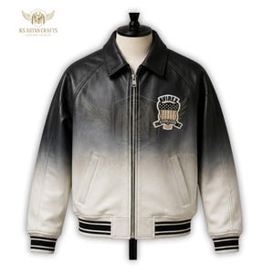 K&ouml;nnte beinhalten: Eine schwarz-wei&szlig;-Ombre-Lederjacke mit Rei&szlig;verschluss vorne und geripptem Kragen und Manschetten. Die Jacke hat einen Aufn&auml;her auf der Brust mit dem Text "AVIREX" und einem amerikanischen Flaggen-Design. Die Jacke wird auf einer Schaufensterpuppe pr&auml;sentiert.
