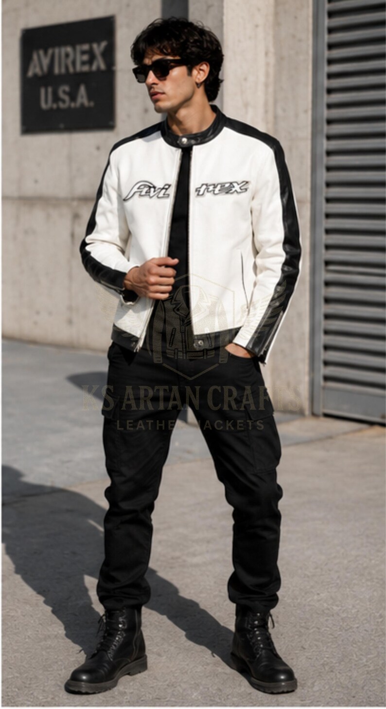 May include: A white and black leather jacket with the text "Avi Rex U.S.A." and "Avi Rex" on the front. The jacket has black sleeves and a black collar. The person is wearing black pants and black boots.