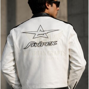 May include: White leather jacket with black accents and a star logo on the back. The jacket features the "Avirex" logo and the text "Spartan Crafts Leather Jackets". The jacket has a zipper on the sleeves.