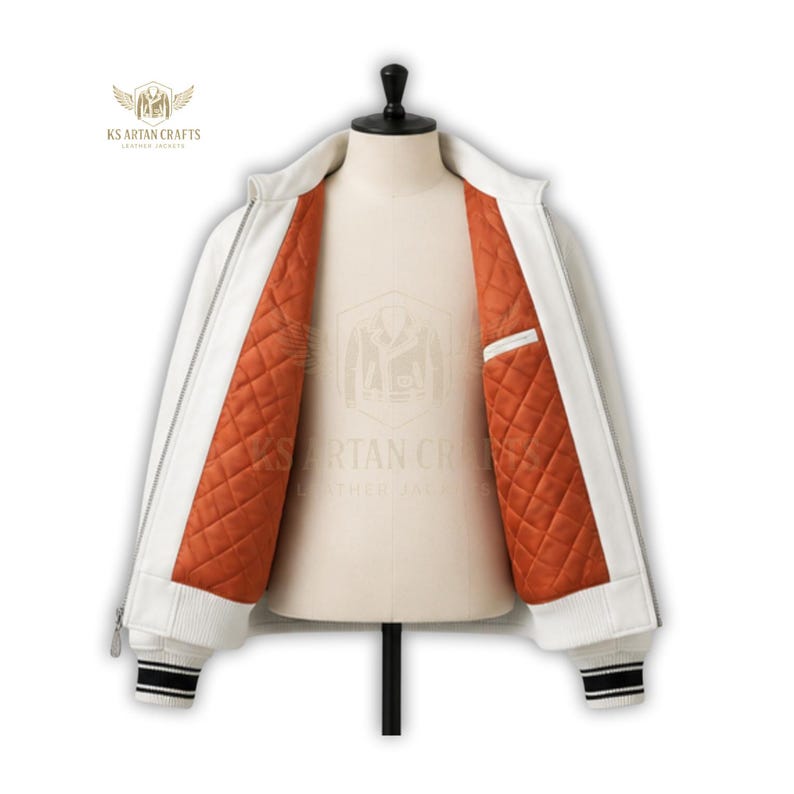 May include: White leather jacket with a ribbed collar, cuffs, and hem. The jacket features a zipper closure and a quilted orange lining. The cuffs have black and white stripes. The jacket is displayed on a mannequin. The brand logo is visible on the upper left.