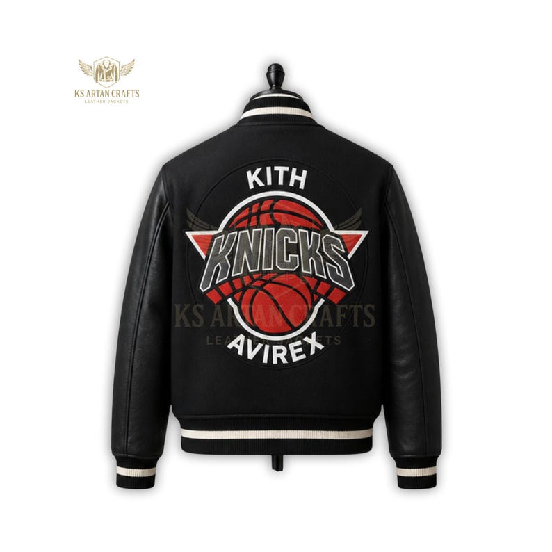 May include: Black varsity jacket with leather sleeves and a white and black striped collar and cuffs. The back features a large circular patch with the text "KITH" above a basketball and the word "KNICKS". The brand name "AVIREX" is below the basketball.