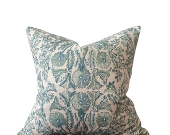 May include: Square throw pillow with a floral pattern in shades of blue and green on a cream background. The pillow has a soft, textured appearance and is likely made of linen or a similar fabric. The design features stylized flowers and leaves.