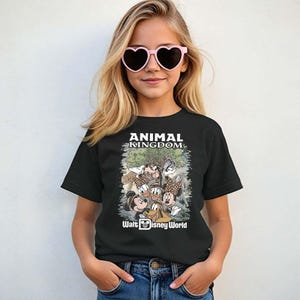 May include: Black t-shirt featuring the text "ANIMAL KINGDOM" above a graphic of Disney characters. The graphic includes Mickey Mouse, Minnie Mouse, Donald Duck, and Goofy. The words "Walt Disney World" are printed below the graphic.