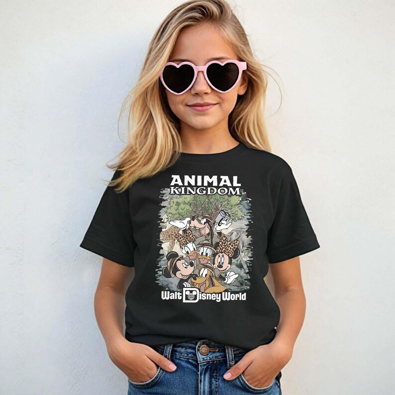May include: Black t-shirt featuring the text "ANIMAL KINGDOM" above a graphic of Disney characters. The graphic includes Mickey Mouse, Minnie Mouse, Donald Duck, and Goofy. The words "Walt Disney World" are printed below the graphic.
