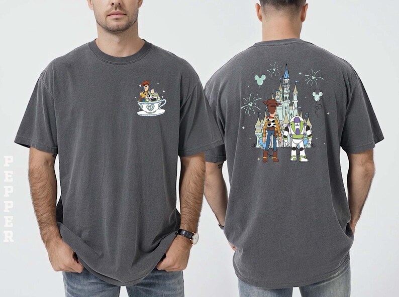 K&ouml;nnte beinhalten: Dunkelgraues T-Shirt mit einem Cartoon-Design von Woody und Buzz Lightyear. Die Vorderseite zeigt Woody und Buzz in einer Teetasse, und die R&uuml;ckseite hat ein Schloss und Feuerwerk. Das T-Shirt ist aus weichem Material.