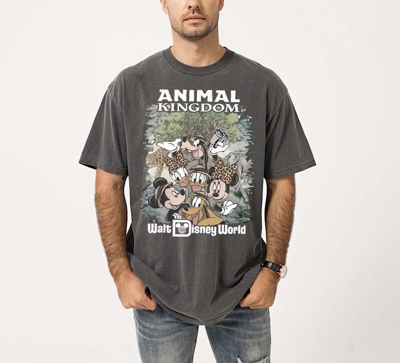 May include: Dark gray t-shirt featuring the text "ANIMAL KINGDOM" and "Walt Disney World." The shirt has a graphic of Mickey Mouse, Minnie Mouse, Donald Duck, Goofy, and other characters. The shirt is worn by a person.