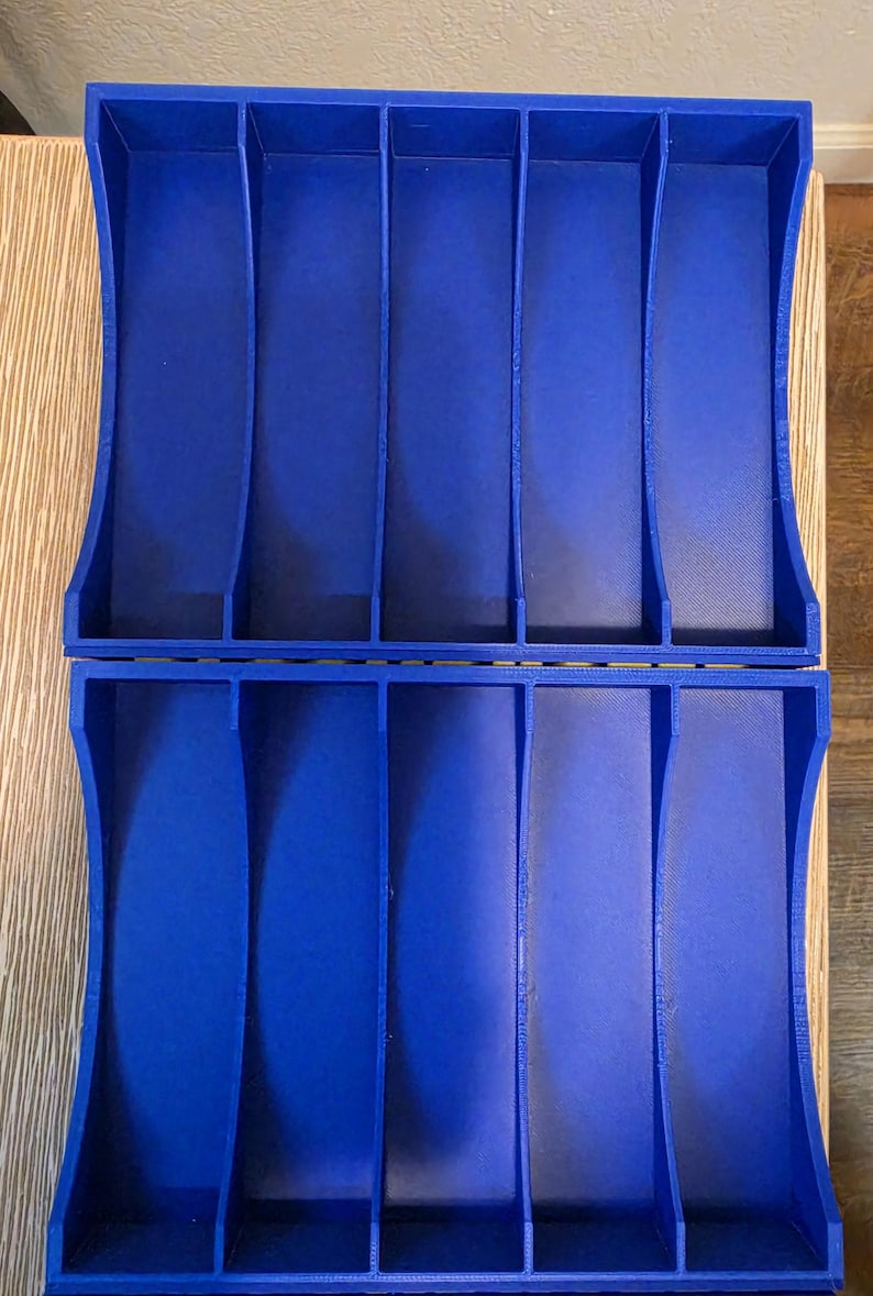 Peut inclure: Deux organisateurs en plastique bleu assortis, chacun avec six compartiments verticaux. Les organisateurs ont des c&ocirc;t&eacute;s incurv&eacute;s et un int&eacute;rieur textur&eacute;. Ils sont probablement con&ccedil;us pour ranger de petits objets.
