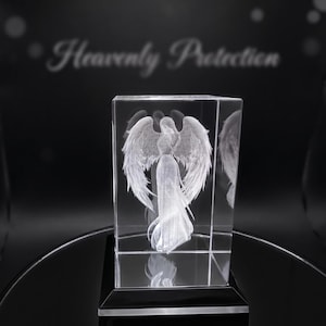 May include: A clear, rectangular crystal sculpture featuring an angel with outstretched wings. The angel is intricately detailed, with flowing robes. The base is black, and the background has the text "Heavenly Protection".