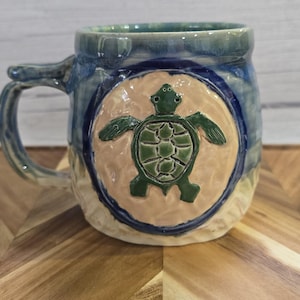 May include: A set of three ceramic nesting bowls in shades of blue, green, and white. The bowls feature a speckled glaze and a simple, modern design. The largest bowl is approximately 6 inches in diameter.