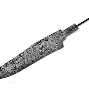 May include: A knife blade featuring a complex black and white swirling pattern across its surface. The blade has a pointed tip, a curved cutting edge, and a narrow metal tang extending from the handle area, showcasing a distinct Damascus steel style.