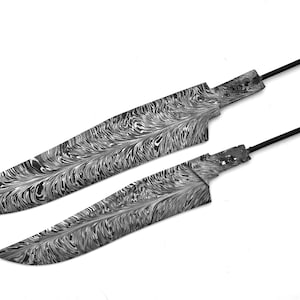 May include: Two knife blades featuring a distinct black and white swirling pattern across the metal surface. Each blade has a pointed tip, a curved cutting edge, and a narrow, unadorned metal tang extending from the base for handle attachment.
