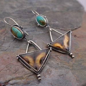 May include: A pair of silver dangle earrings featuring oval turquoise cabochons at the top and larger triangular brown and cream agate stones at the bottom. The stones are set in twisted silver wire frames with silver hook ear wires.