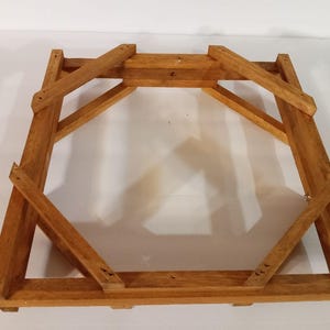 May include: Wooden frame with a square base and a hexagonal top. The frame is made of unfinished wood and has a natural color.