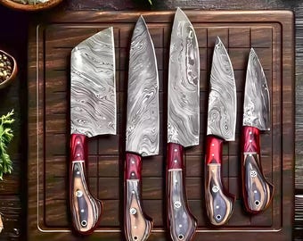 May include: A set of five kitchen knives with patterned steel blades and red and wood-tone handles. The knives are arranged on a wooden cutting board, showcasing their sharp edges and detailed craftsmanship. The blades have a unique, swirling pattern.