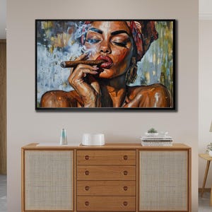 May include: A framed painting depicting a woman with dark skin smoking a cigar. She is wearing a headscarf and large earrings. The artwork uses a warm colour palette with shades of brown, red, and gold, and a black frame.