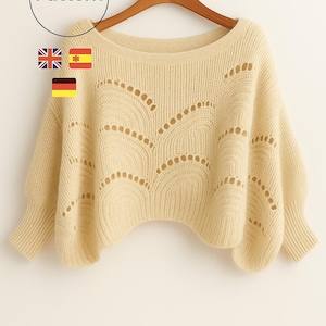 May include: Cream-colored knit sweater with a boat neck and long sleeves. The sweater features a decorative openwork pattern across the chest and upper sleeves. The word "Pattern" is in a circle in the upper left corner.