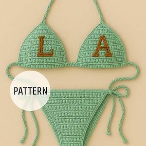 Puede incluir: Conjunto de bikini tejido a ganchillo en color verde claro. La parte superior presenta las letras "LA" en color marrón. La braguita del bikini tiene lazos laterales. La palabra "PATTERN" está en un círculo blanco.