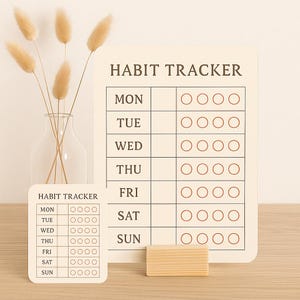 Może przedstawiać: Beżowy tracker nawyków z napisem "HABIT TRACKER" i dniami tygodnia. Każdy dzień ma cztery kółka do śledzenia nawyków. Mniejsza wersja trackera jest również obecna, wraz z małym drewnianym klockiem.