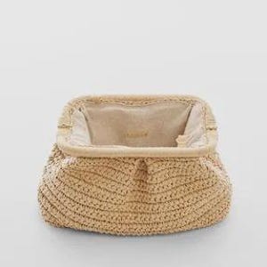 Op de afbeelding: Een beige geweven clutch-tas met een open bovenkant, die een lichtgekleurd interieur onthult. De tas heeft een afgeronde vorm en een getextureerd, handgemaakt uiterlijk, wat wijst op een natuurlijk vezelmateriaal.