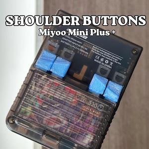 Puede incluir: Un dispositivo de juego portátil transparente con botones de hombro azules. El dispositivo tiene una pantalla que muestra una imagen colorida. El texto en el dispositivo incluye "SHOULDER BUTTONS Miyoo Mini Plus +" y especificaciones técnicas.