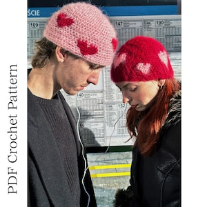 May include: Two people wearing matching crochet hats with heart designs. One hat is pink with red hearts, the other is red with pink hearts. The hats are part of a crochet pattern, as indicated by the text on the left side of the image.