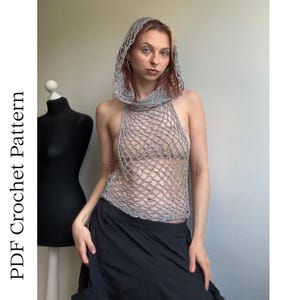 May include: A silver metallic crochet hooded halter top with an open net stitch pattern. The garment features a hood and a sleeveless design. The text "PDF Crochet Pattern" is visible on the left side of the image next to a black mannequin.