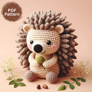 Op de afbeelding: Een gehaakte egel met een beige lichaam, grijze stekels en een zwarte neus en ogen. De egel houdt een groene tak vast en heeft roze wangen. De afbeelding bevat de tekst "PDF Pattern" in een cirkelvormig ontwerp.