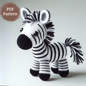 Może przedstawiać: Pluszowa zabawka w kształcie zebry wykonana na szydełku z czarno-białymi paskami. Zebra ma czarny nos, czarne kopyta i puszysty ogon z czarno-białymi paskami.