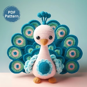 Peut inclure: Un jouet amigurumi en crochet en forme de paon avec un corps rose, des plumes de queue bleues et vertes et une crête bleue. Le jouet est posé sur une surface rose. Modèle PDF.