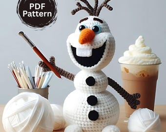 May include: A crocheted snowman with a carrot nose, black buttons, and twig arms. The snowman is holding a pen and is next to a cup of coffee with whipped cream and balls of white yarn. The image includes the text "PDF Pattern".