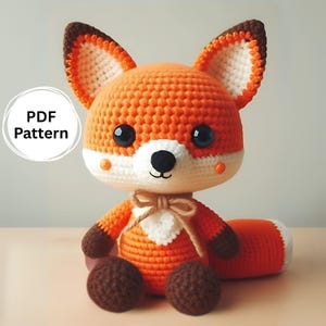 Pode incluir: Um brinquedo de pelúcia de raposa laranja de crochê com orelhas marrons e barriga branca. A raposa tem olhos pretos e um nariz marrom. O brinquedo está sentado em uma superfície marrom claro. Padrão PDF.