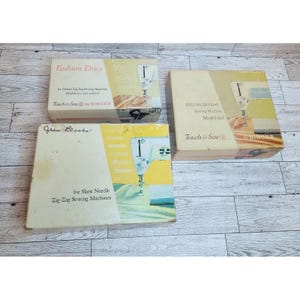 Puede incluir: Tres cajas de accesorios de máquinas de coser Singer vintage. Las cajas son de color beige y amarillo con texto e ilustraciones de máquinas de coser. Las cajas están etiquetadas como "Fashion Discs", "Deluxe Zig Zag Sewing Machine Model 628" y "for Slant Needle Zig-Zag Sewing Machines".