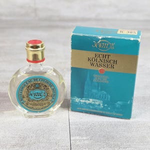 May include: A clear glass bottle of 4711 Echt Kölnisch Wasser with a gold cap and a blue and gold label, accompanied by its matching teal and gold rectangular cardboard box featuring an illustration of a cathedral and the text 4711 Echt Kölnisch Wasser.