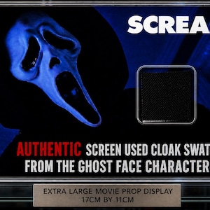 Op de afbeelding: Een ingelijste filmrekwisietendisplay met het woord "SCREAM" in het wit. Het bevat een blauw Ghostface-maskersilhouet en een zwart stoffen staal. De tekst luidt "AUTHENTIC SCREEN USED CLOAK SWATCH FROM THE GHOST FACE CHARACTER!". De display meet 17 cm bij 11 cm.