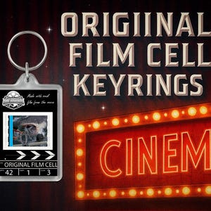 May include: A clear film cell keyring with a movie still inside. The keyring has a silver metal ring and the text "ORIGINAL FILM CELL KEYRINGS". A red "CINEMA" sign with yellow lights is in the background.