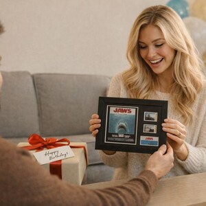 A man is presenting a framed picture of a shark to a smiling woman, who is holding the framed picture.