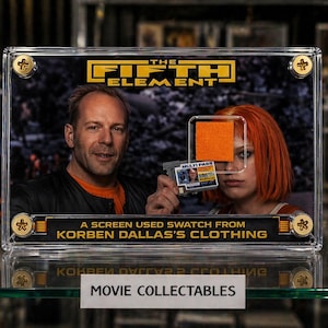 Pode incluir: Um item de colecionador de filmes emoldurado de "O Quinto Elemento" com atores. A moldura inclui uma amostra da roupa de Korben Dallas e o texto "MOVIE COLLECTABLES". O fundo mostra outras lembranças de filmes.