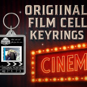 Könnte beinhalten: Ein Schlüsselanhänger mit einer Filmzelle, die ein Filmbild enthält. Der Schlüsselanhänger hat einen silbernen Metallring und einen rechteckigen Kunststoffrahmen. Der Text "ORIGINAL FILM CELL KEYRINGS" ist darüber abgebildet. Im Hintergrund befindet sich ein rotes Kinozeichen.