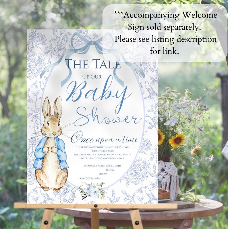 May include: A blue and white baby shower sign with a Peter Rabbit illustration. The sign says "The Tale of Our Baby Shower" and "Once Upon a Time".