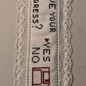 Può includere: Segnalibro bianco fatto a mano a punto croce con un delicato bordo in pizzo. Il segnalibro presenta il testo "SAVE YOUR PROGRESS?" con le opzioni "YES" e "NO" e un'icona di computer rossa.