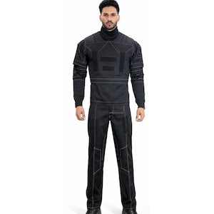 Op de afbeelding: Een zwart tweedelig outfit met witte stiksels. De top is een coltrui met lange mouwen en geometrische ontwerpen. De broek heeft rechte pijpen met bijpassende stiksels. De outfit wordt gedragen met zwarte schoenen.