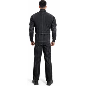 Op de afbeelding: Zwart jumpsuit met witte stiksels en geometrische patronen op de mouwen. De outfit bestaat uit een jas en broek en wordt van achteren getoond. Het model draagt zwarte schoenen.