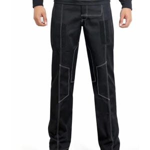 Op de afbeelding: Zwarte broek met witte stiksels en verstevigde patches. De broek heeft een recht model en is gemaakt van duurzaam materiaal. De stiksels cre&euml;ren een geometrisch patroon op de knie&euml;n en zijkanten.