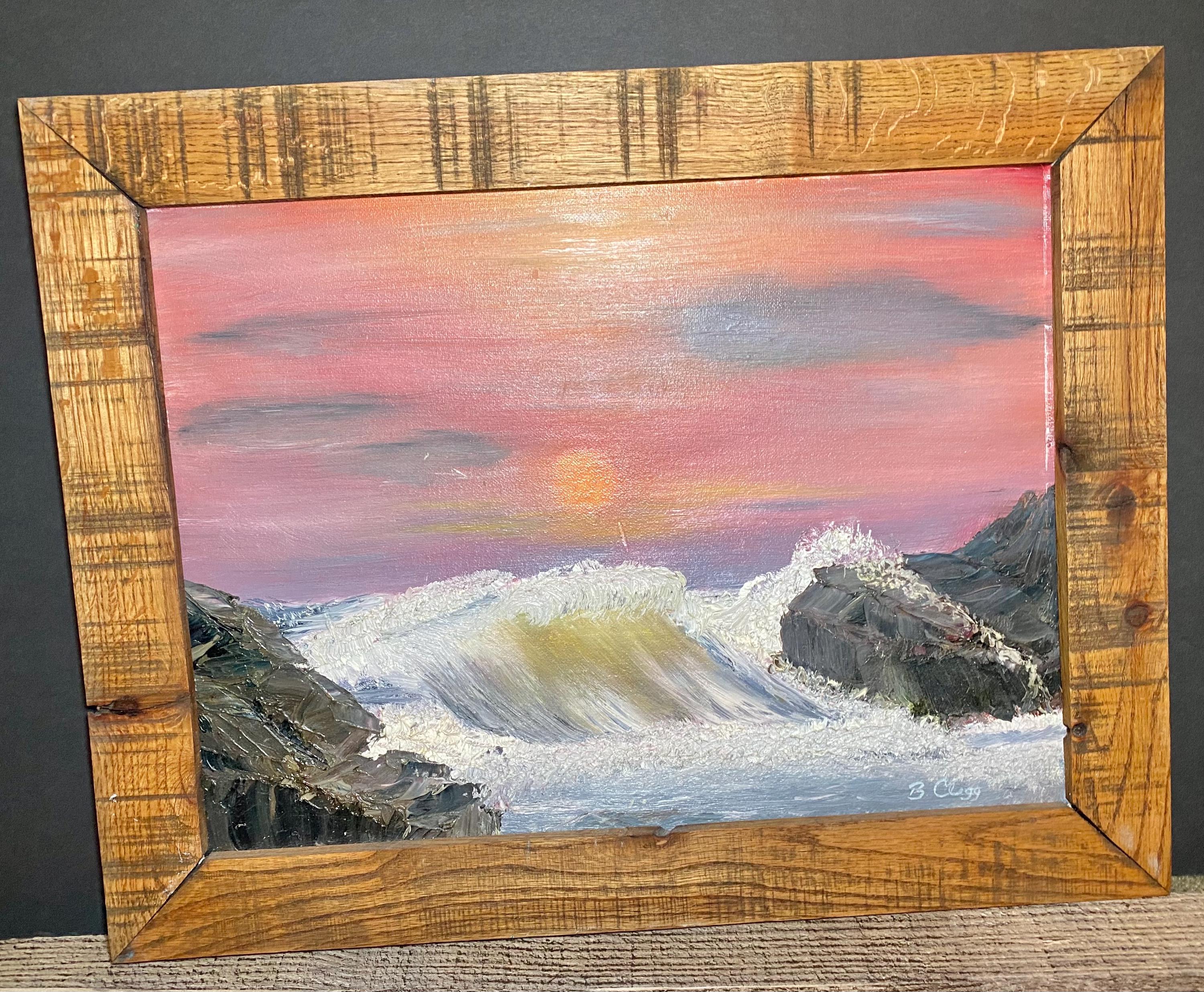 May include: Oil painting of ocean waves crashing against rocks under a pink and orange sunset sky. The artwork is framed in a rustic, light-brown wooden frame. The artist's signature is in the bottom right corner.