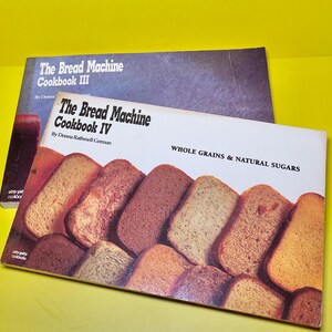 May include: Two cookbooks titled "The Bread Machine Cookbook III" and "The Bread Machine Cookbook IV" are displayed. The cover of Cookbook IV features images of various bread slices and the text "Whole Grains & Natural Sugars."